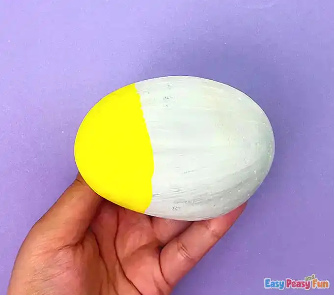 A white painted rock with the front third painted in bright yellow for the fish's head.