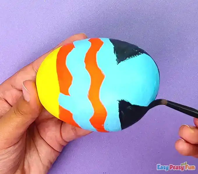 Using a black marker to outline blue patterns.