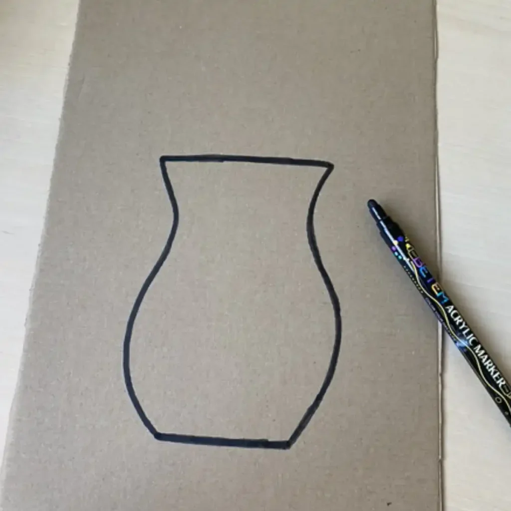 Drawing a vase shape outline on a sheet of cardboard with a black marker