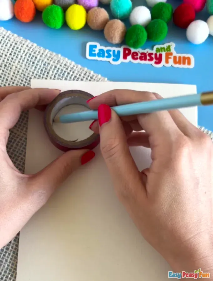Pencil tracing a circle  inside a tape roll on a white cardstock.