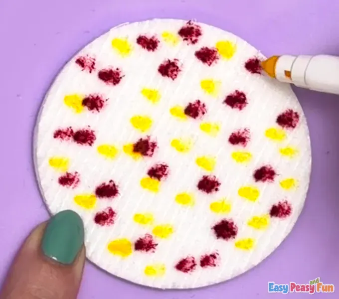 A yellow marker is being used to fill in the gaps between the existing red dots, creating a colorful polka-dot effect.