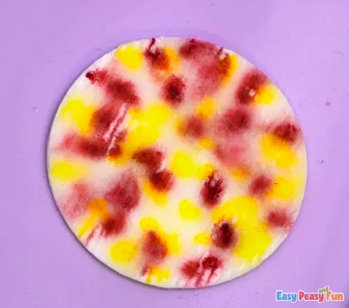 The finished, dried cotton pad now features a vibrant, blended pattern of soft orange, yellow, and red colors.