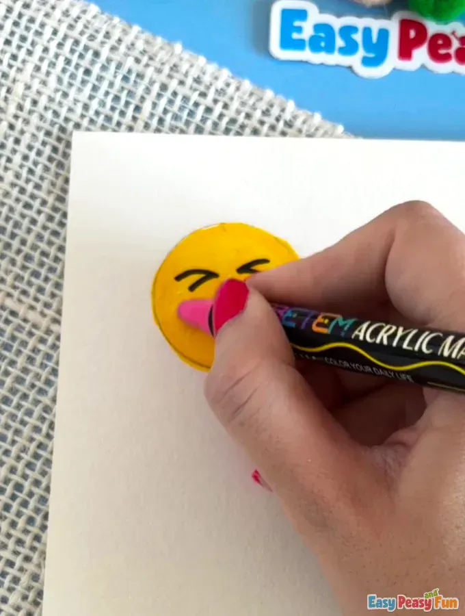 Hand drawing rosy cheeks on a smiley character.
