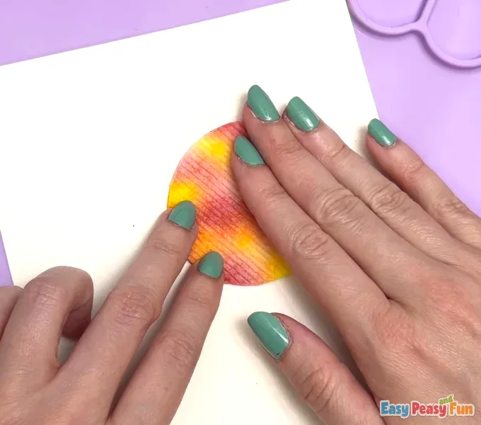 Fingers pressing down gently on the center of the shell to secure it to the cardstock.