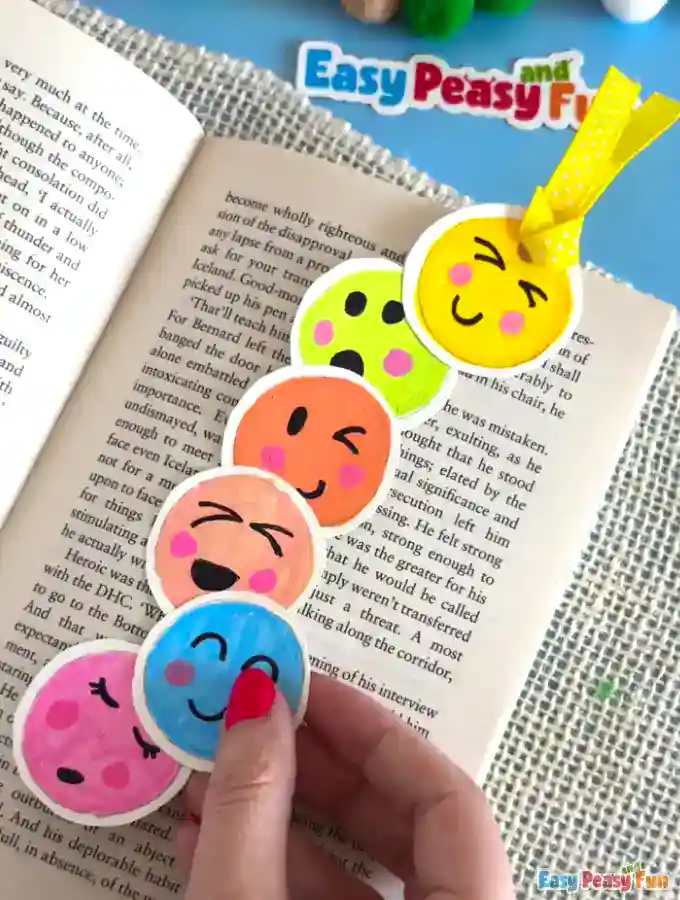 Finished vertical emoji bookmark with a yellow ribbon, placed inside an open book.
