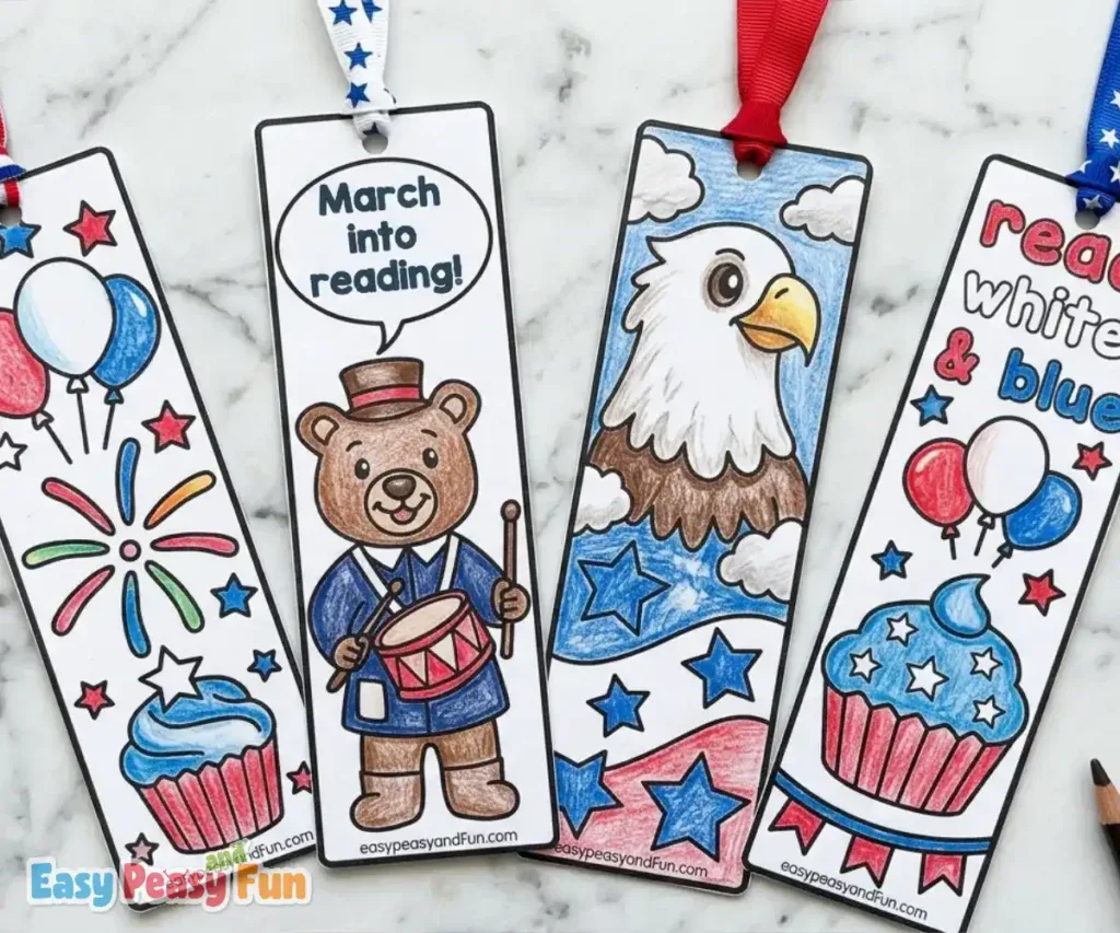 Four completed, hand-colored 4th of July bookmarks with ribbons attached, featuring a festive cupcake with fireworks, a drumming bear, a bald eagle, and patriotic balloons.