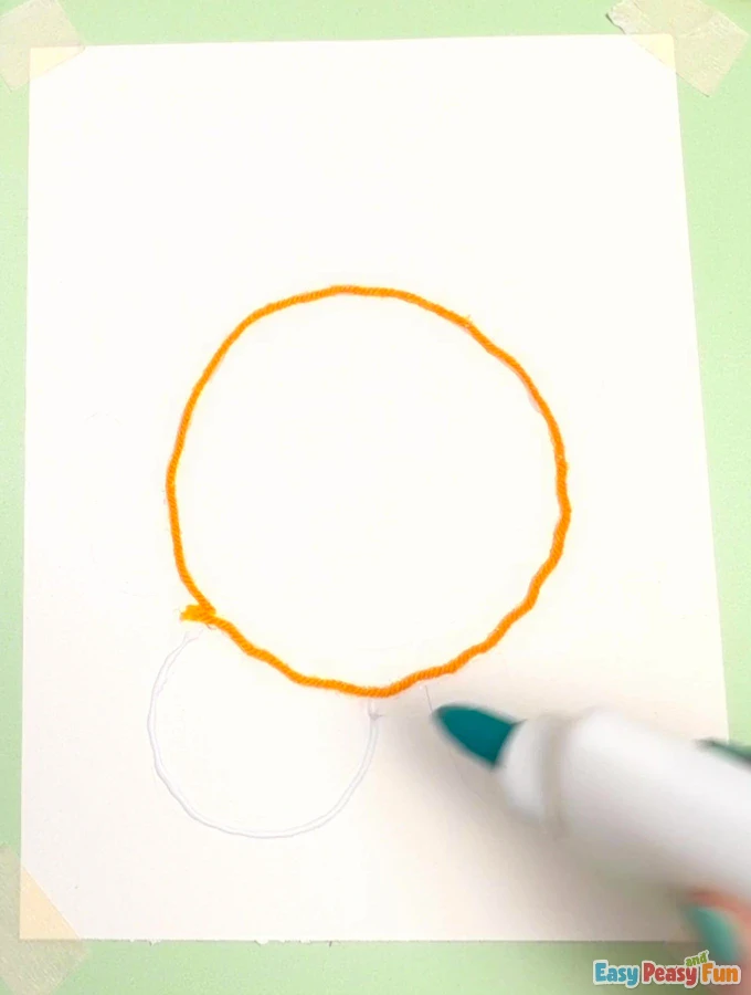 Hand traces the turtle's head and legs with glue.