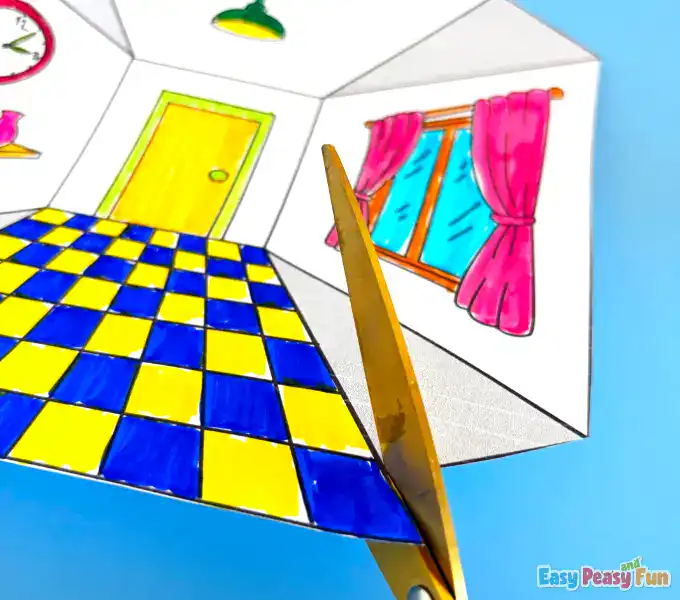 A pair of scissors carefully cutting along the interior dashed lines of the paper.