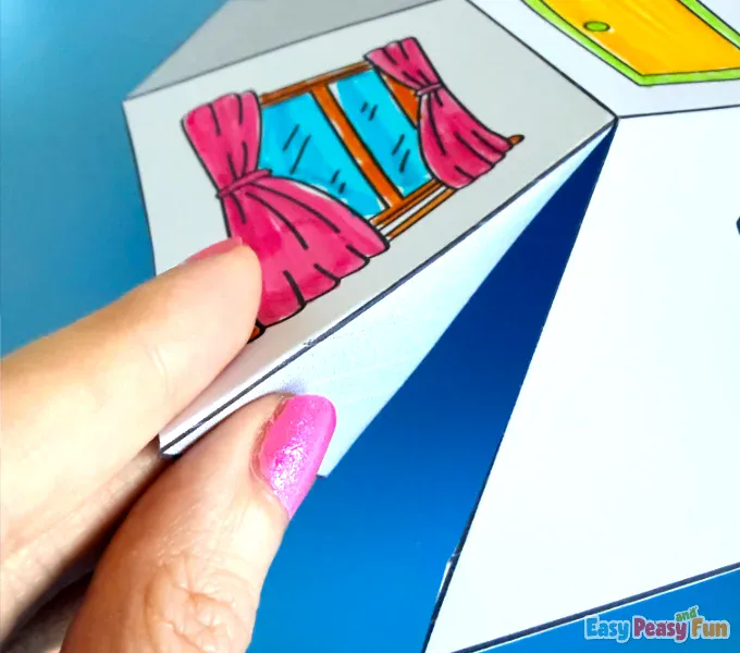 A hand folding paper edges along scored lines to create sharp folds.