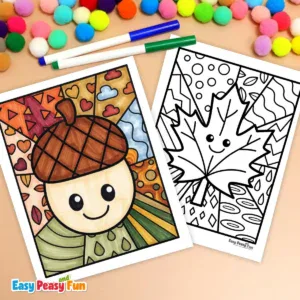 Two markers and colorful pom-poms resting above two fall pop art coloring pages, one featuring a colored acorn and the other a blank maple leaf design.