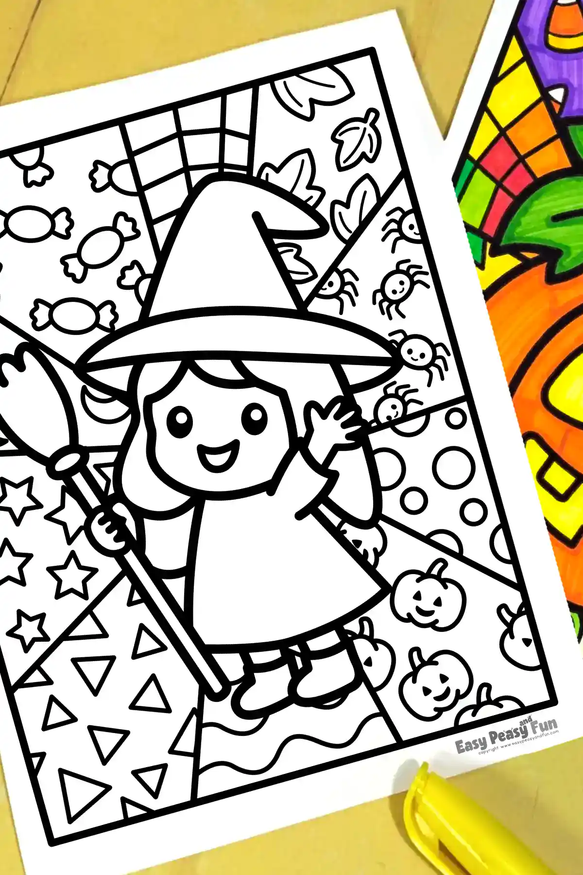 A printed Halloween coloring page featuring a witch holding a broomstick, placed on a table next to a yellow marker.
