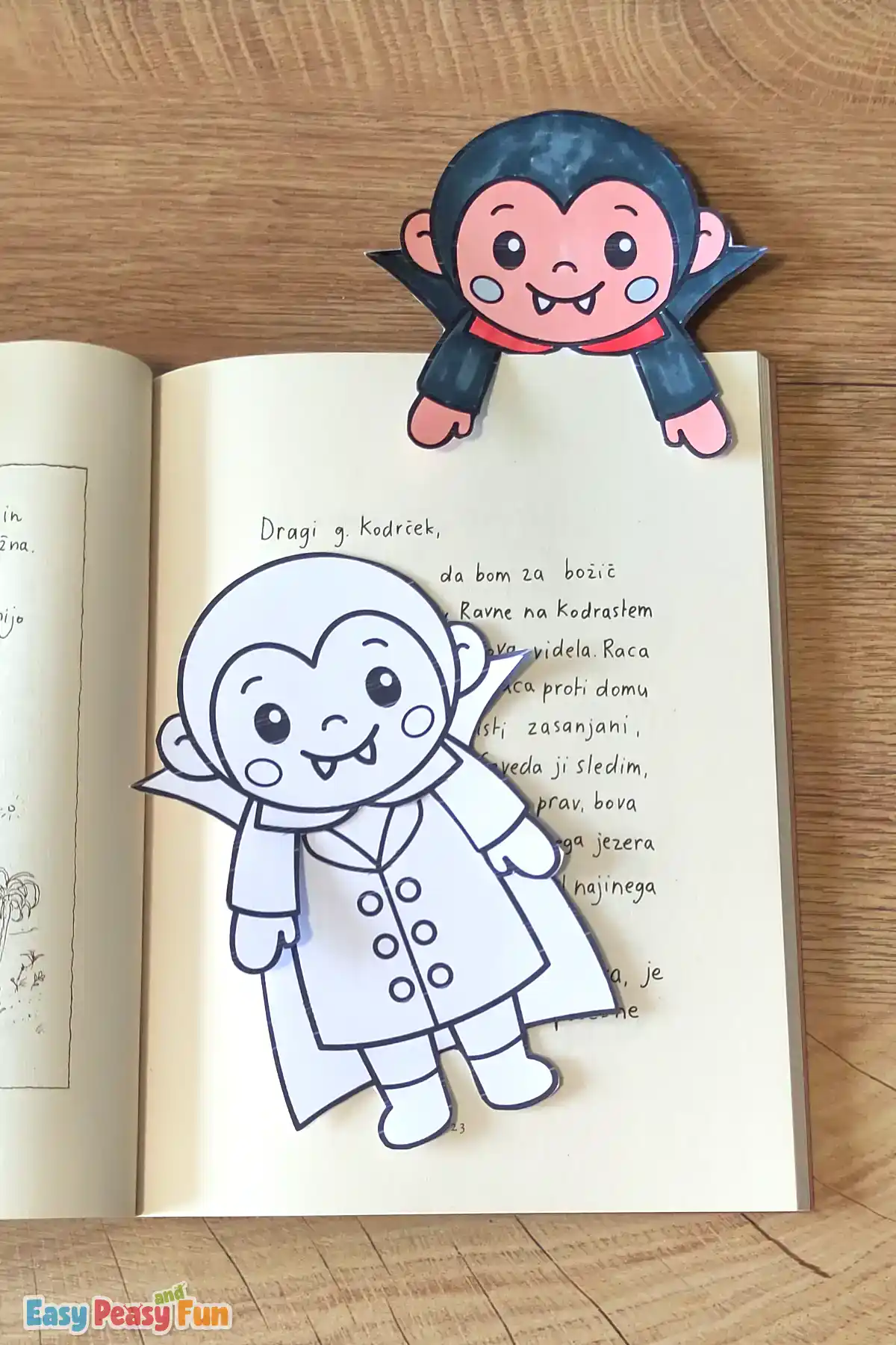 A colored vampire bookmark gripping a book page, with an uncolored vampire template below.