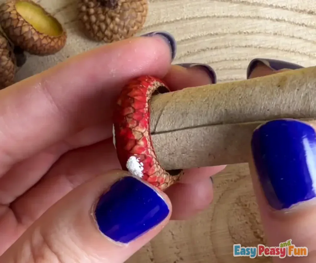 The rolled cardboard stem is pressed securely into the glued cavity of the acorn cap.