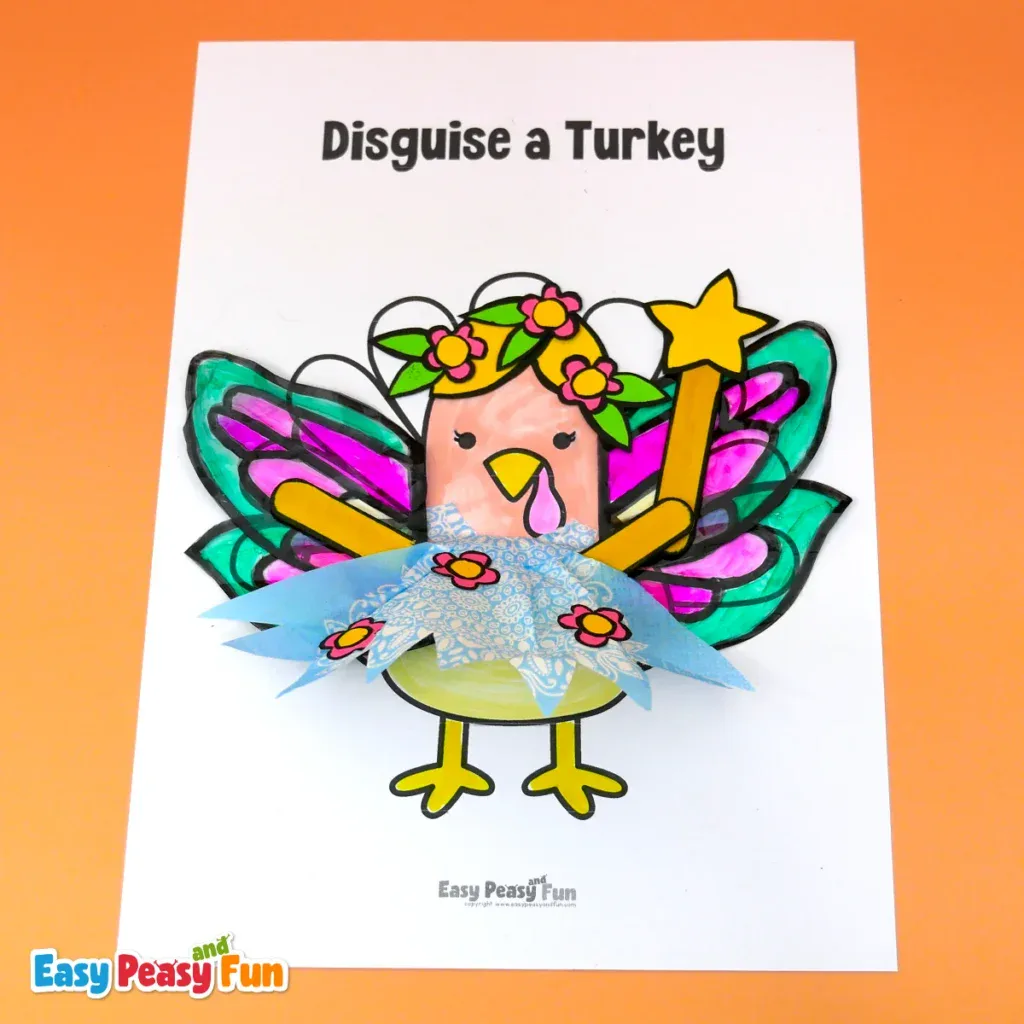 A paper turkey craft disguised as a fairy, complete with a blonde floral wig, colourful wings, a star wand, and a blue patterned paper skirt.