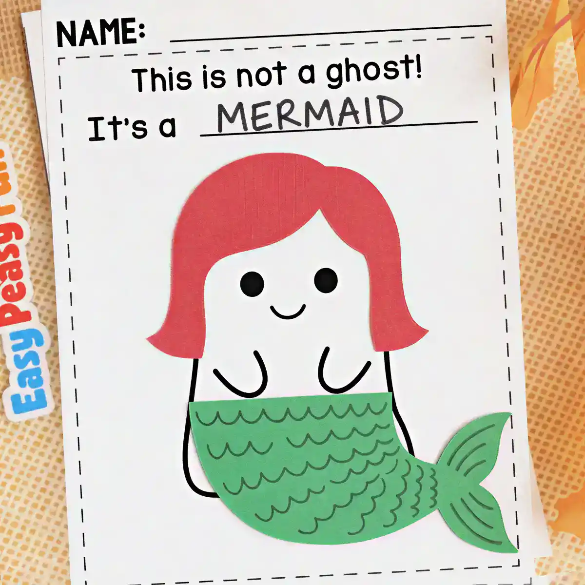 White ghost craft with red paper hair and a green scaled tail made to look like a mermaid.