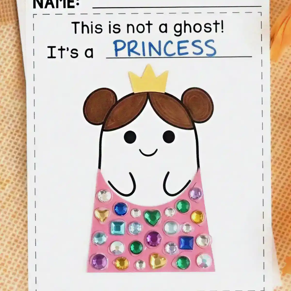 Ghost craft dressed as a princess with a paper crown, brown hair buns, and a pink dress covered in gem stickers.